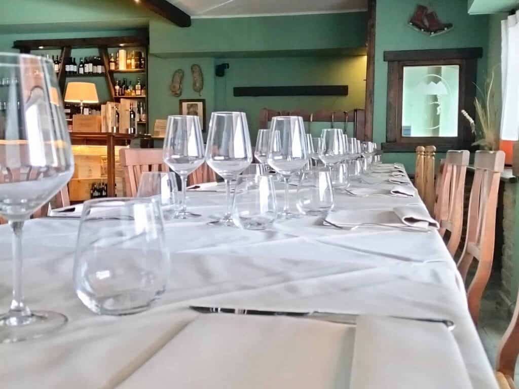 Tavolo elegante con bicchieri e posate in un ristorante piemontese a Sestriere.